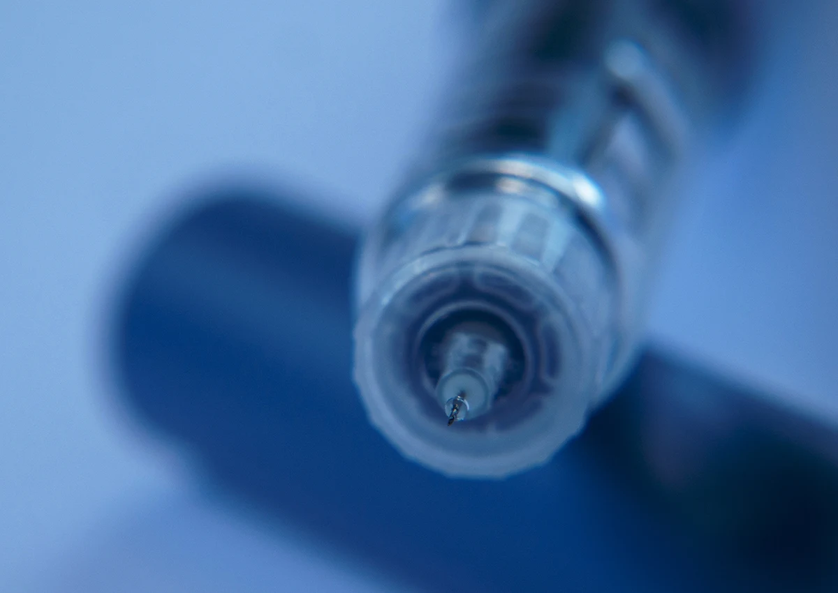 Close-up of a syringe needle tip with a blurred blue background.