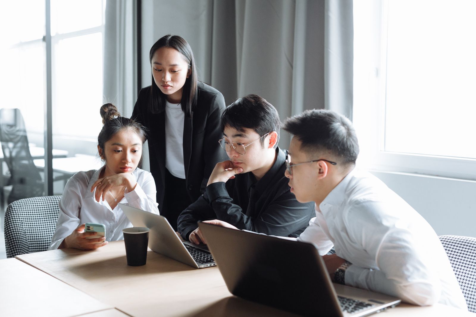 Asian professionals collaborating around a laptop in a bright office