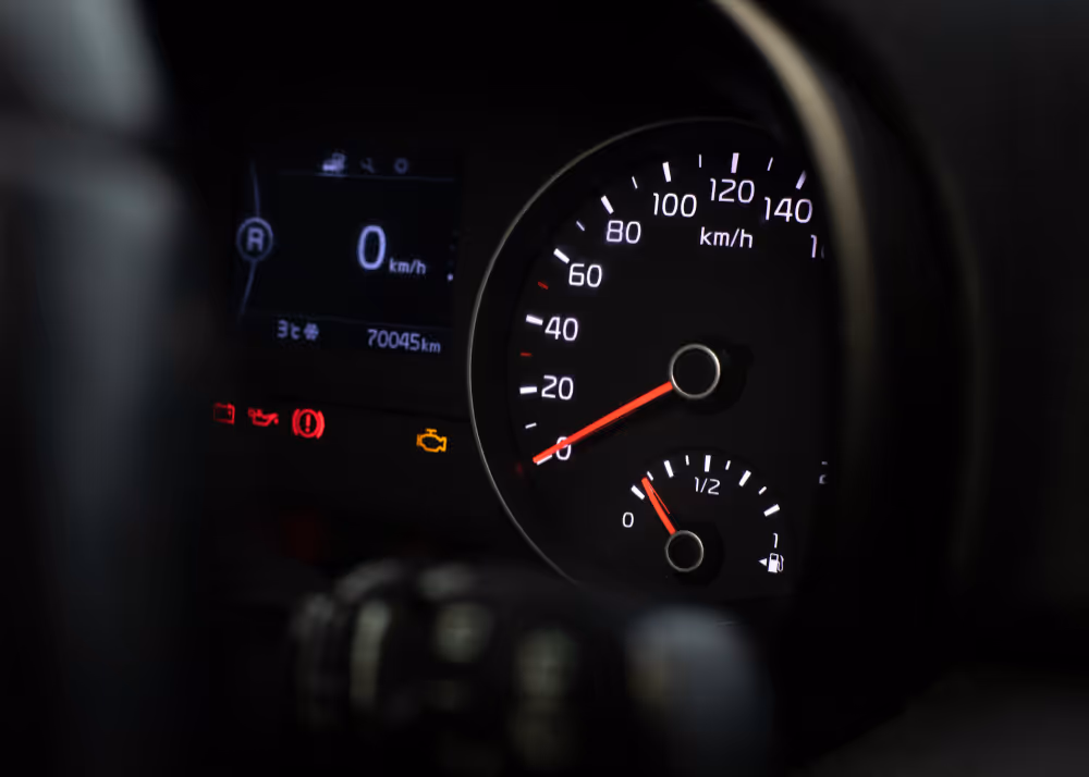 Car dashboard showing speedometer at 0 km/h, fuel gauge near empty, odometer reading 70045 km, and illuminated warning lights.