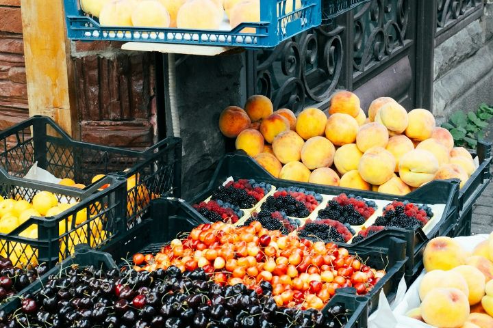Lăzi cu cireșe, piersici și fructe de pădure la o tarabă stradală