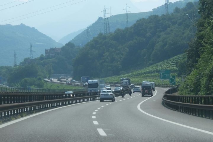 Camioane și autoturisme pe o autostradă printre dealuri cu vii
