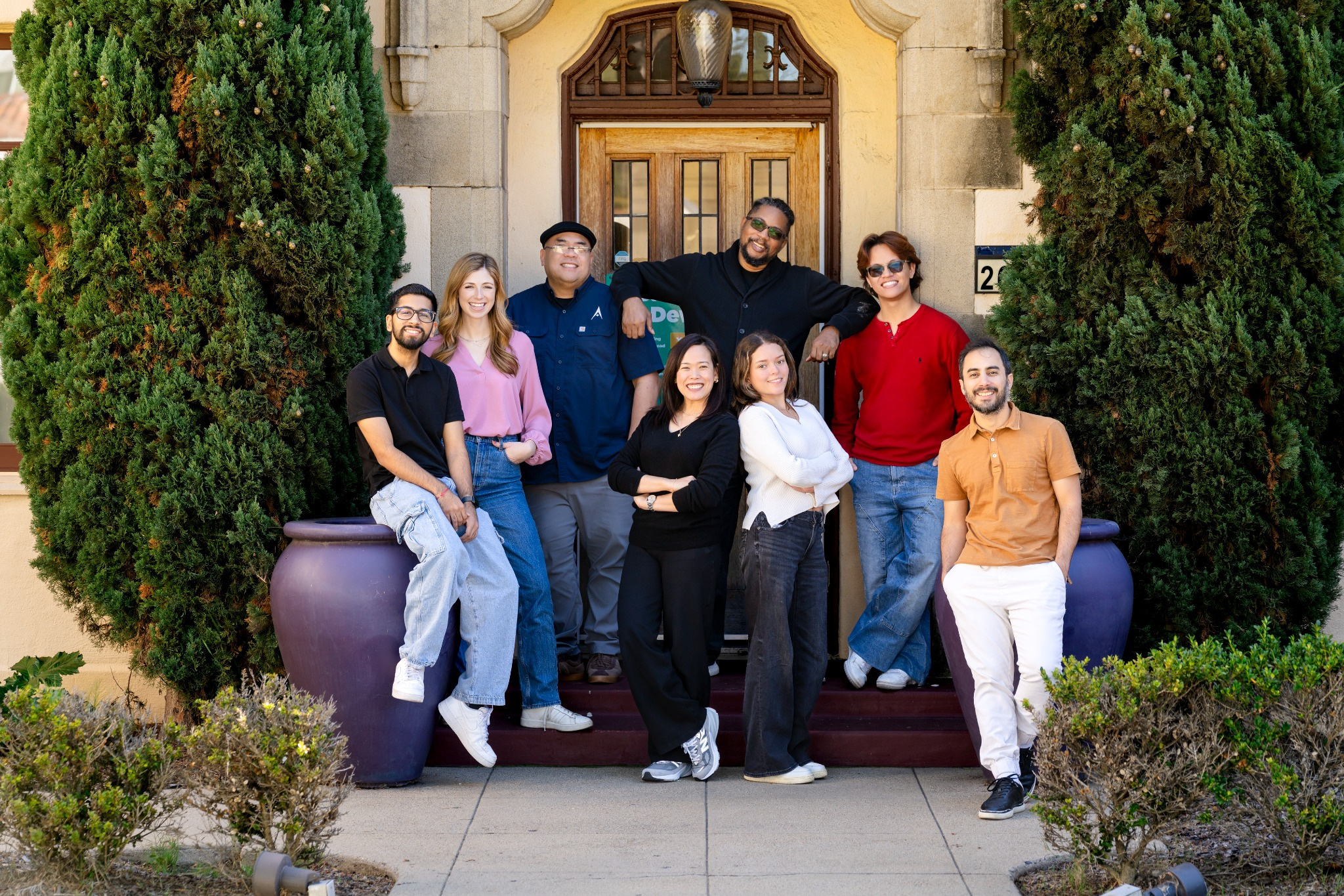The Data Science Alliance team posed together on the front steps of their building, framed by two tall trees
