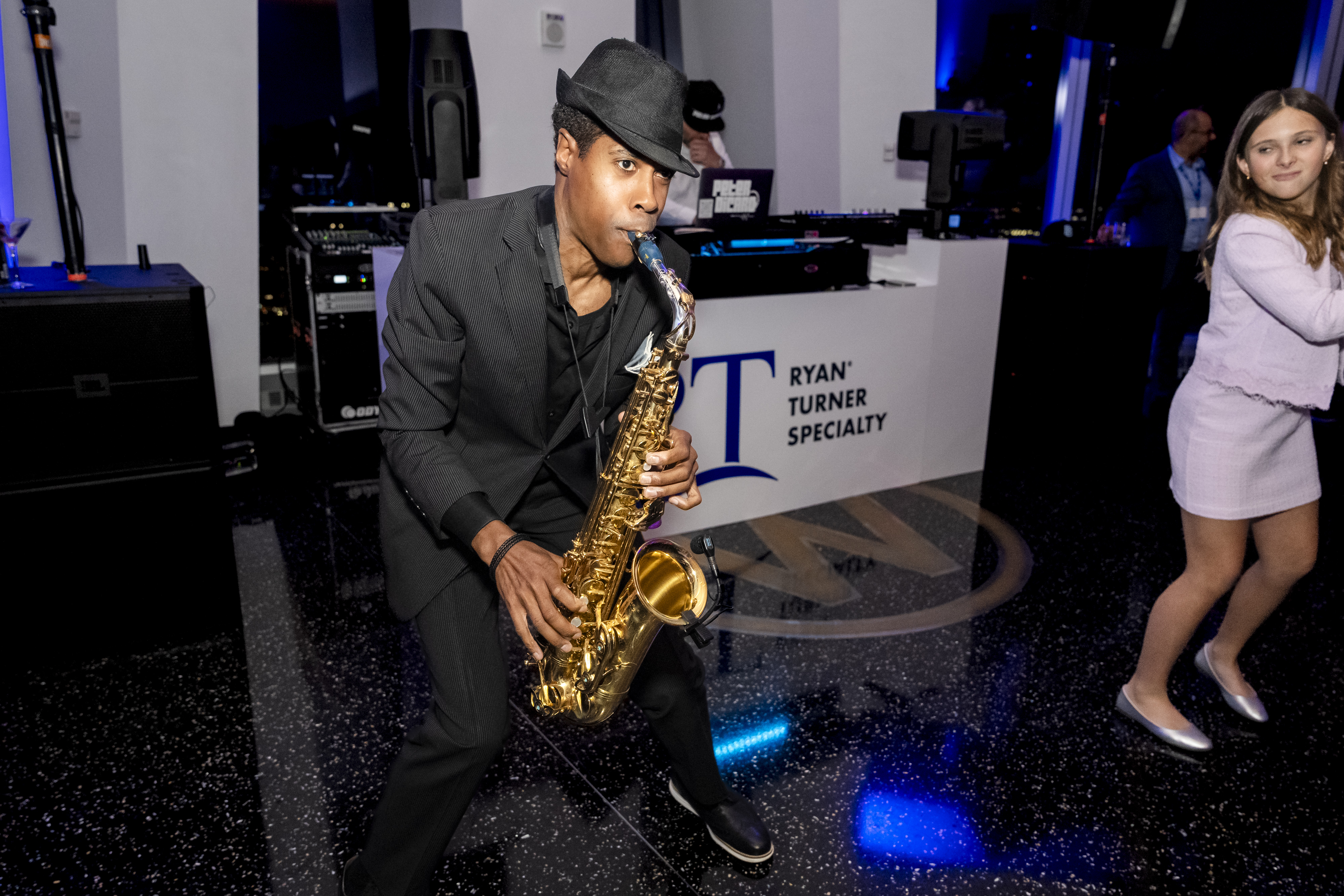 A saxophone player performs on the dance floor in front of the Ryan Turner Specialty DJ booth at RT Specialty's New York City after-party