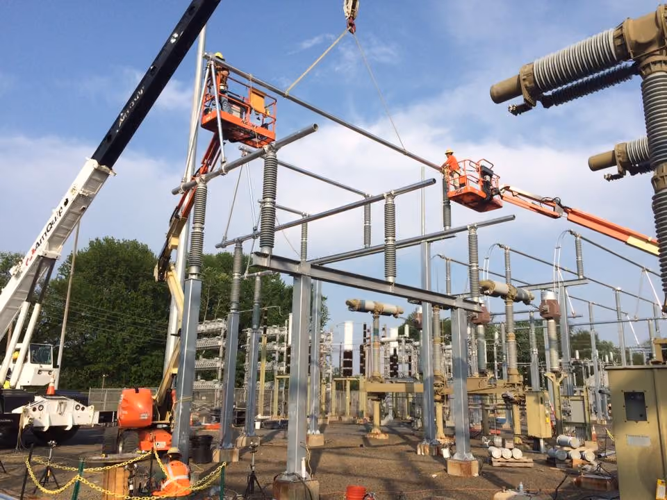 Electrician beside a rack of metal conduit staged on a rooftop