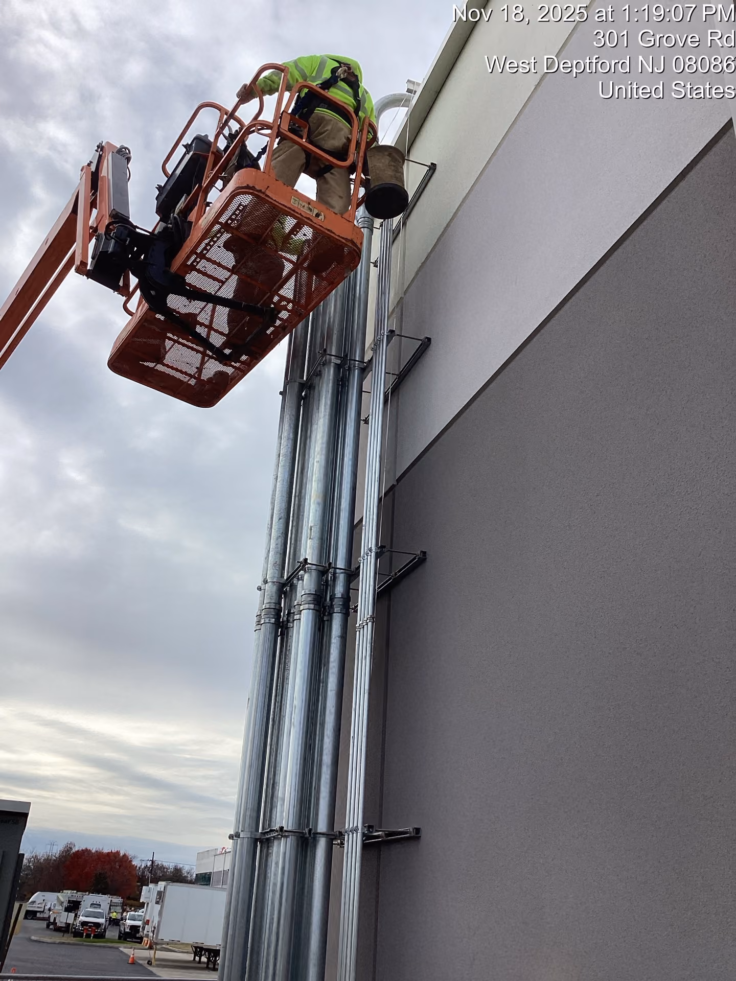 Electrical conduit running up the exterior of a building, with a worker in a lift above