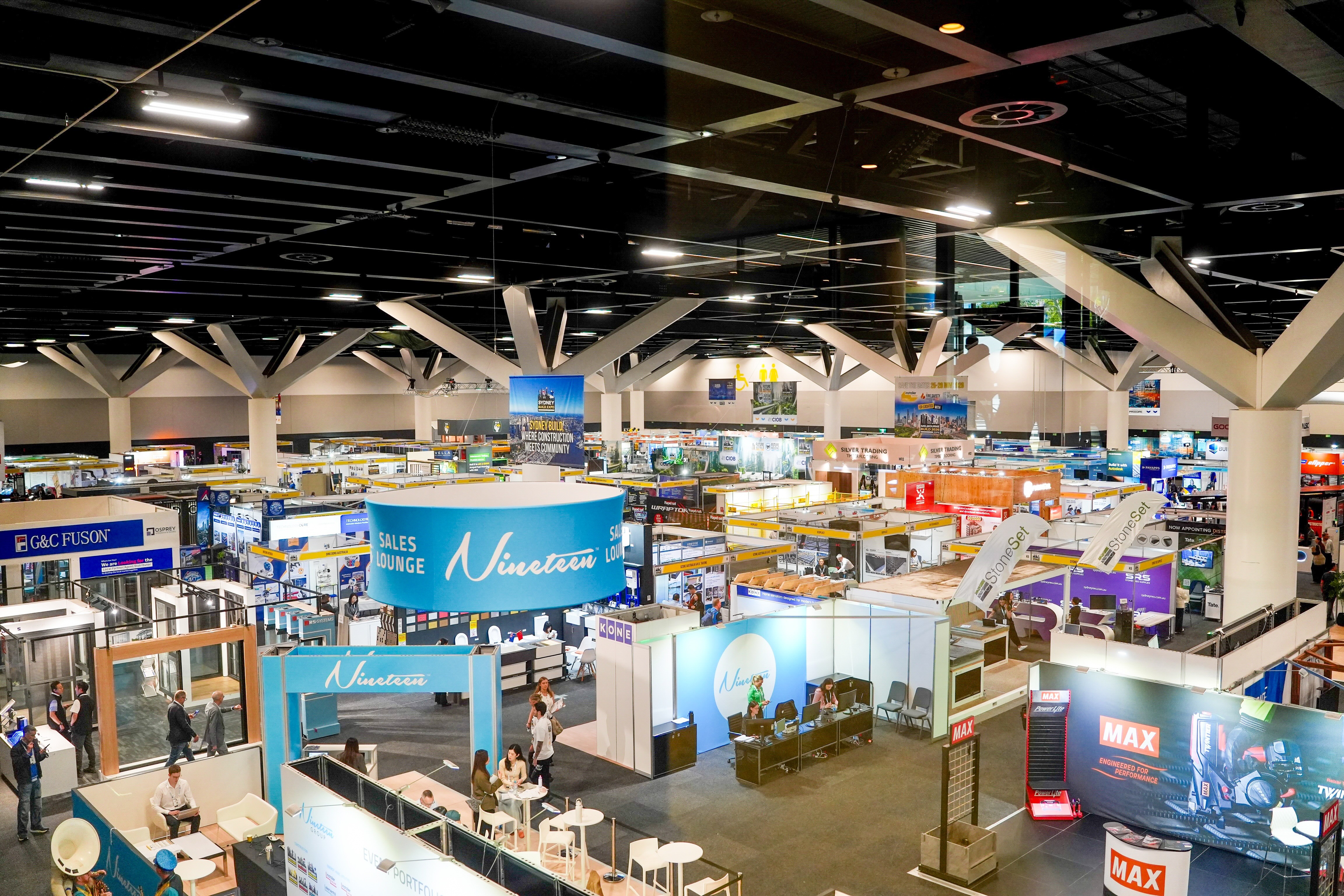 Wide view of a busy trade show floor with booths and attendees