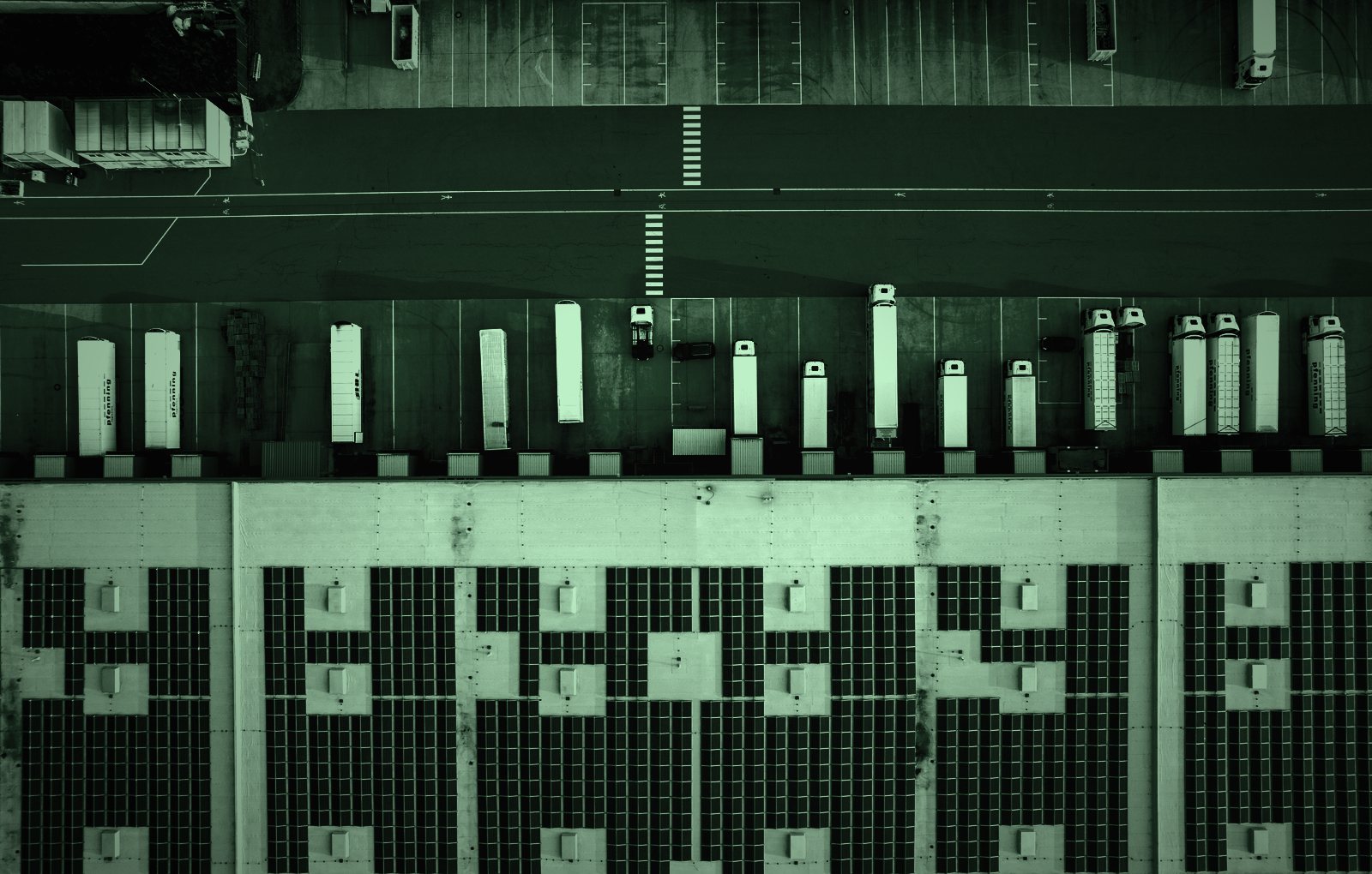Aerial view of trucks at a distribution centre, in dark green tones