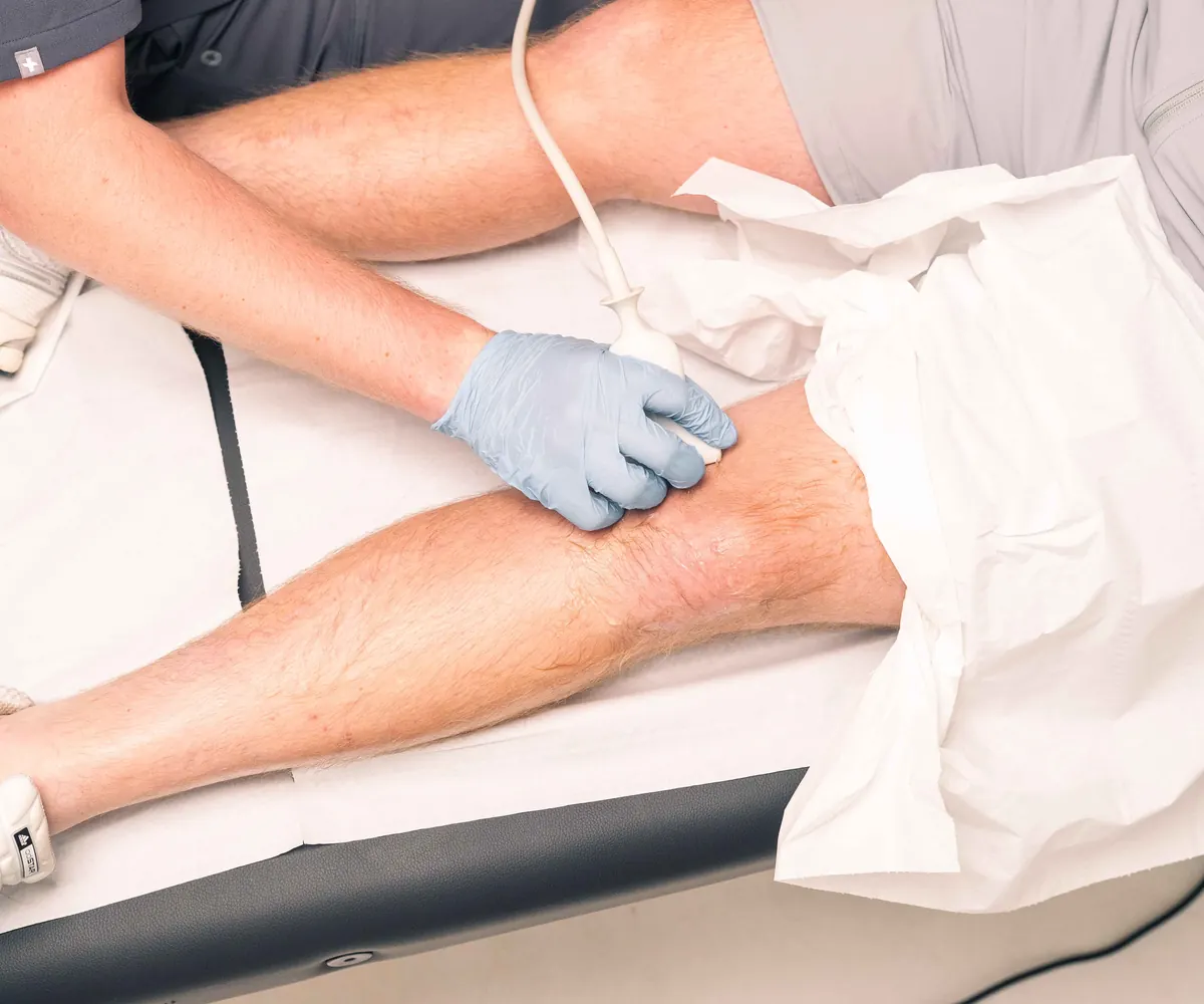 Ultrascan clinician scanning a client's knee with an ultrasound probe