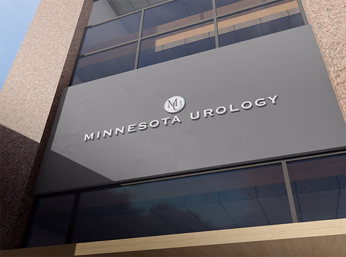 Building facade with Minnesota Urology logo and name on a gray panel under glass windows.