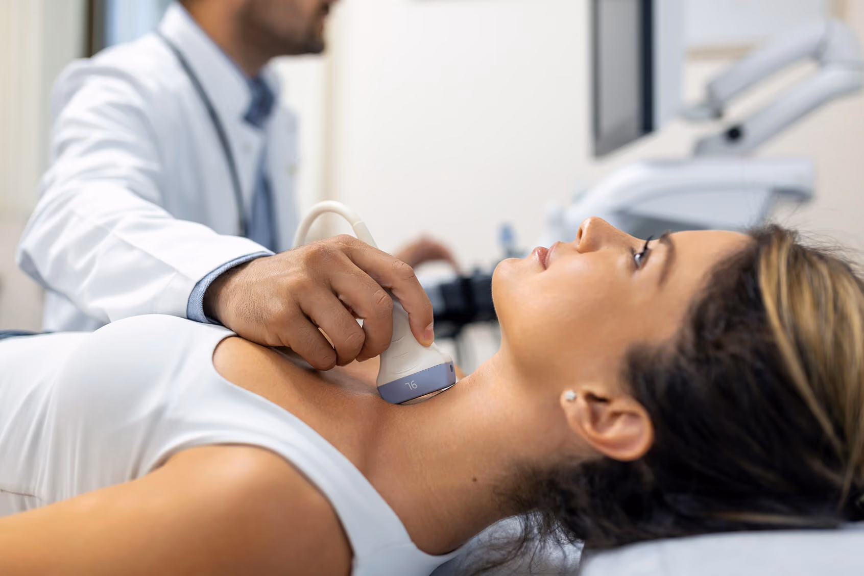 Doctor performing a thyroid ultrasound on a woman's neck