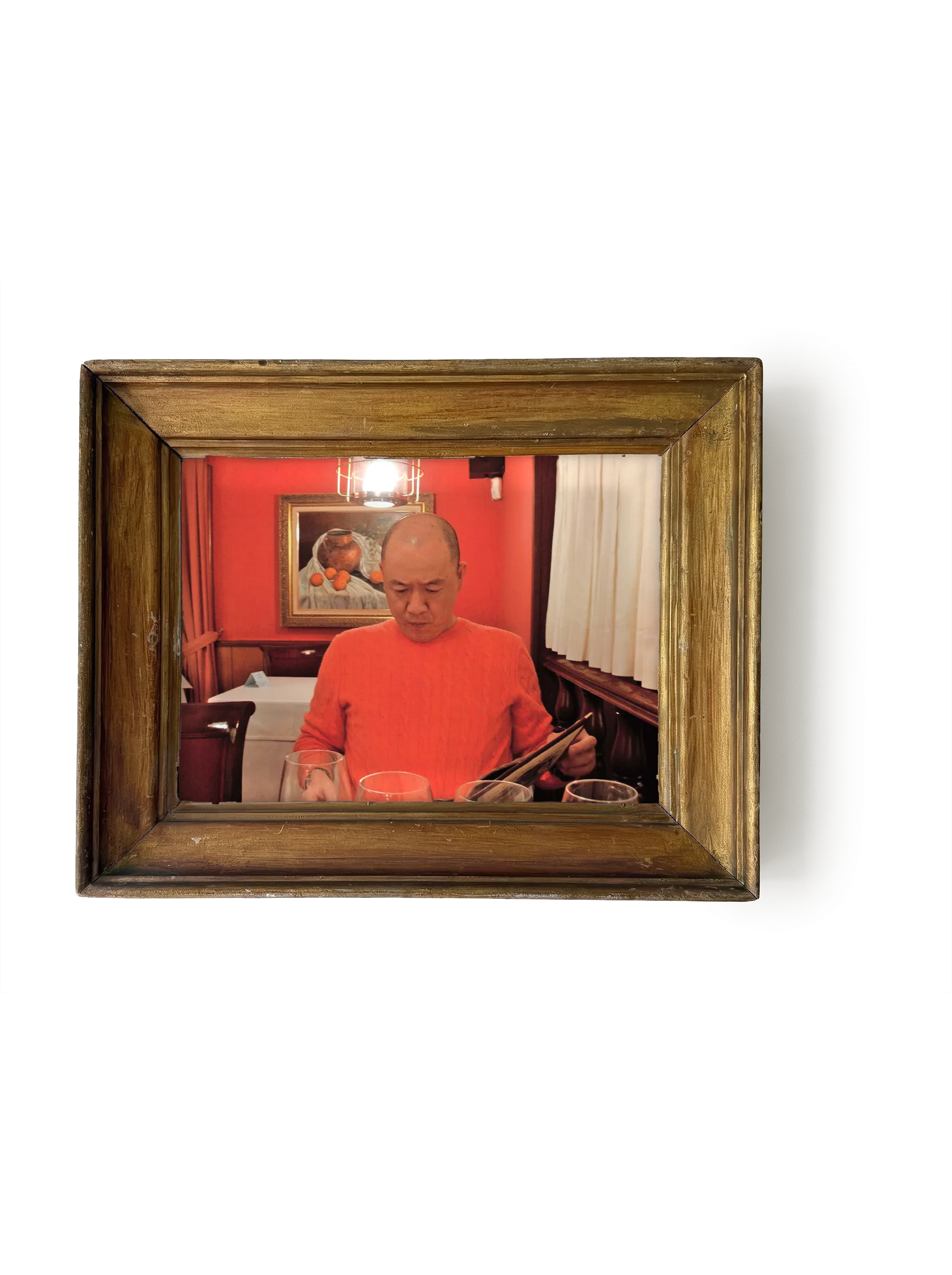 A photograph of Chef Masa in a red dining room, in a gilt frame