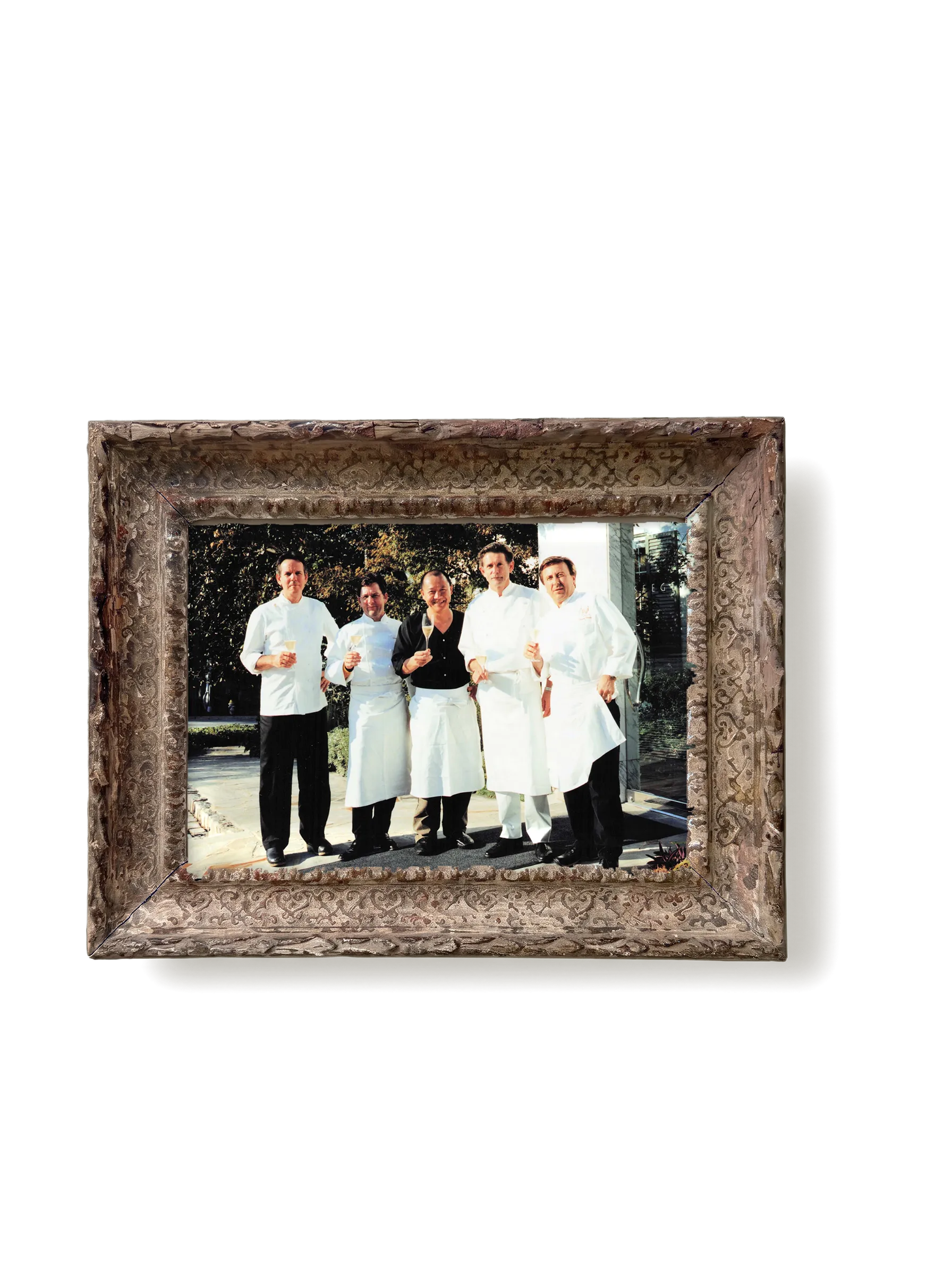 A photograph of Chef Masa with fellow chefs, in a carved gesso frame