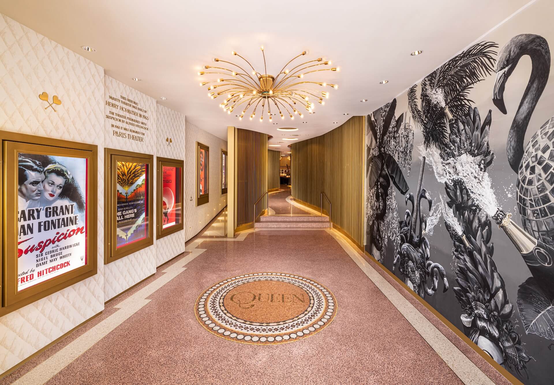 Theater corridor with gold frames, posters and a black and white flamingo mural