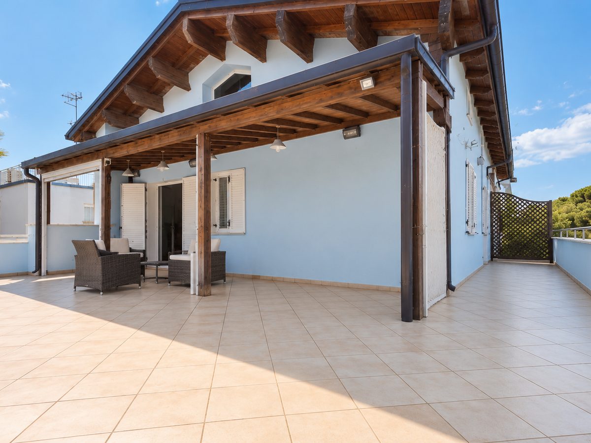 Attico con grande terrazzo, portico in legno e facciata azzurra