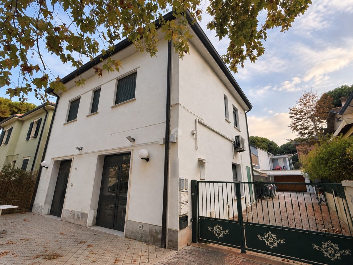 Casa bianca con cancello verde e alberi