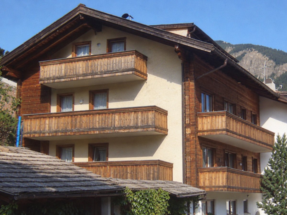 Palazzina di montagna con rivestimento in legno, balconi in legno e vista sui monti