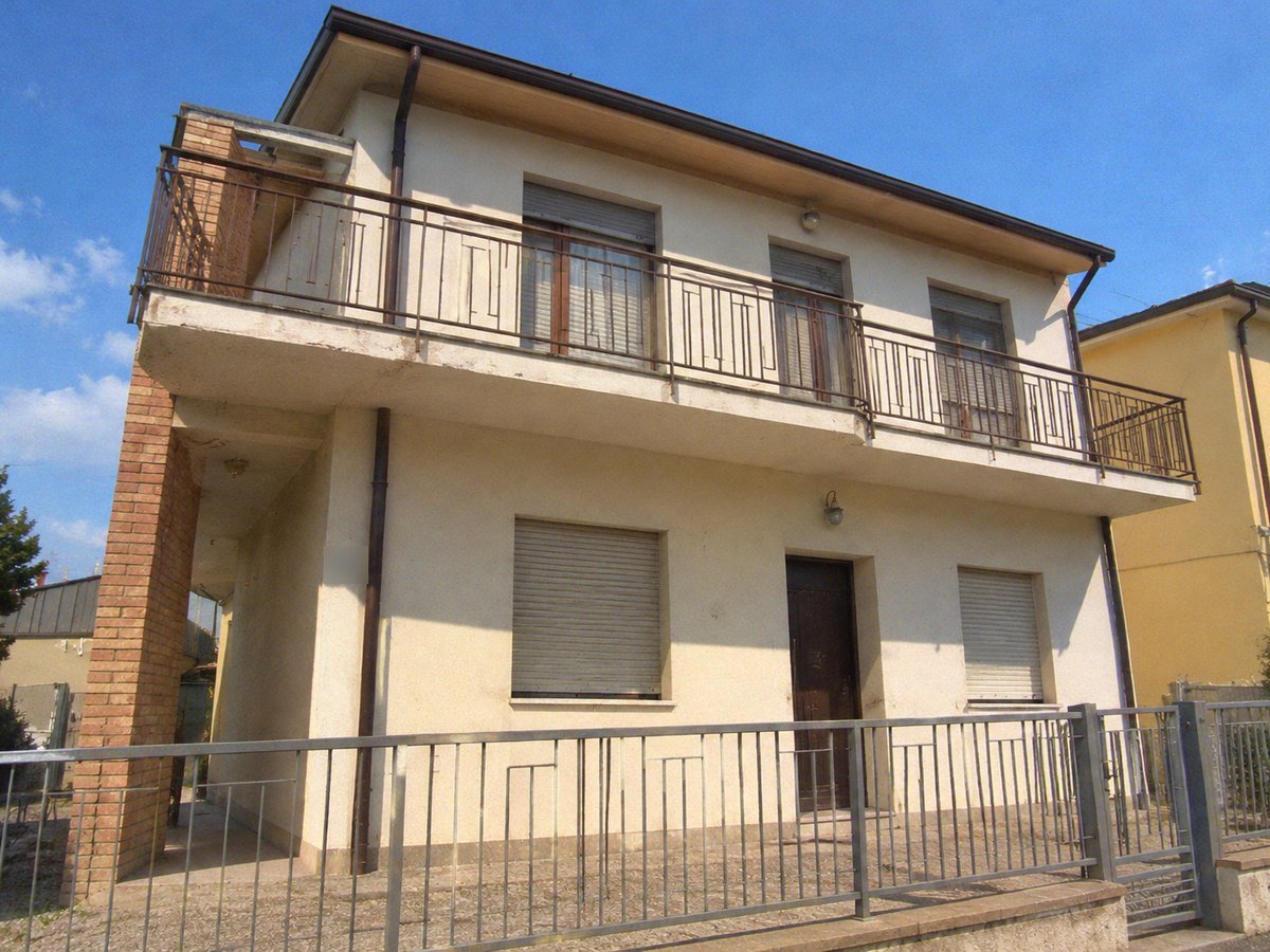 Casa su due piani con facciata crema, colonna in mattoni, balcone lungo e cancellata