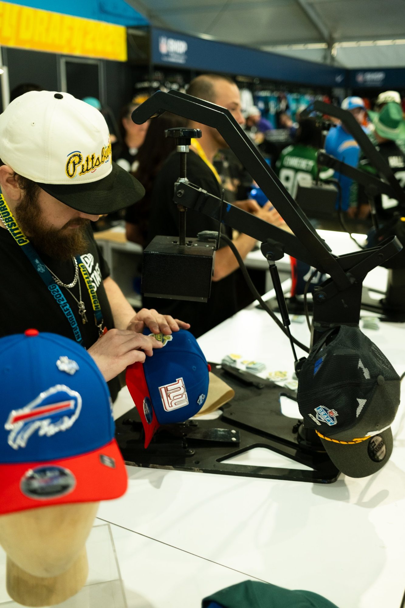 Staff heat-pressing a custom patch onto a cap