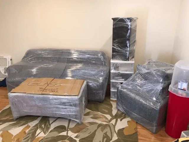 Sofa, armchair, and storage drawers shrink-wrapped and ready to load from a living room