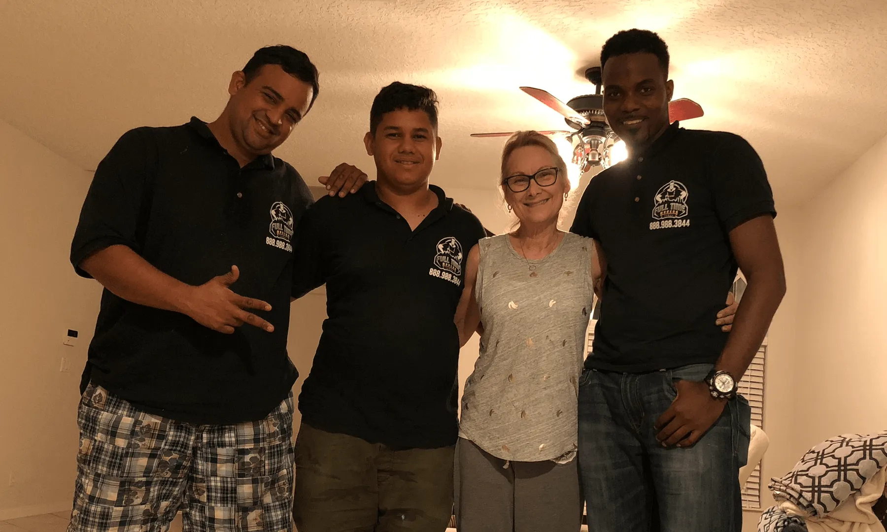 Three Full Time Movers crew members smiling with a customer inside her home