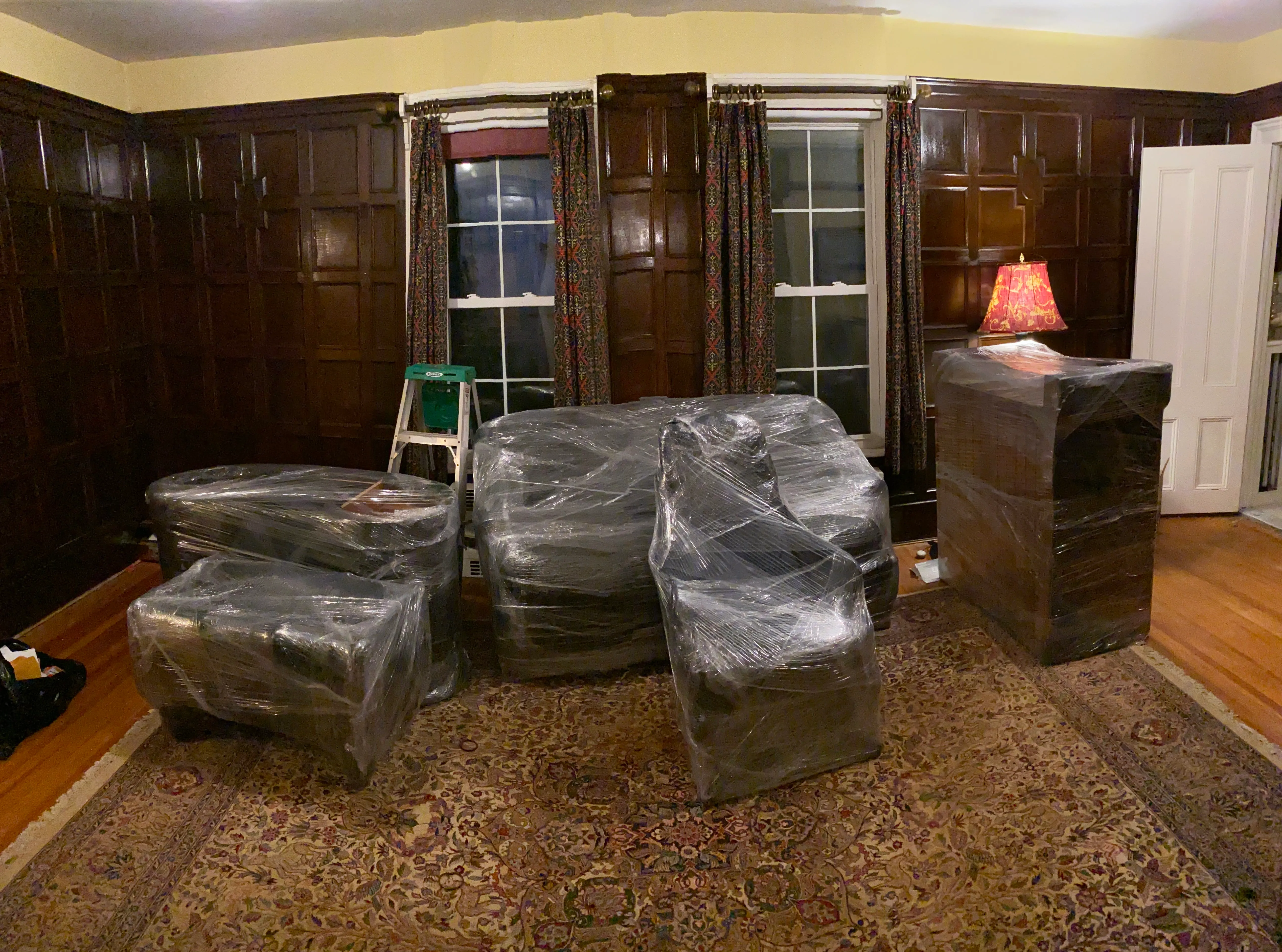 Furniture protected with furniture wrap and ready to move in a wood-paneled living room