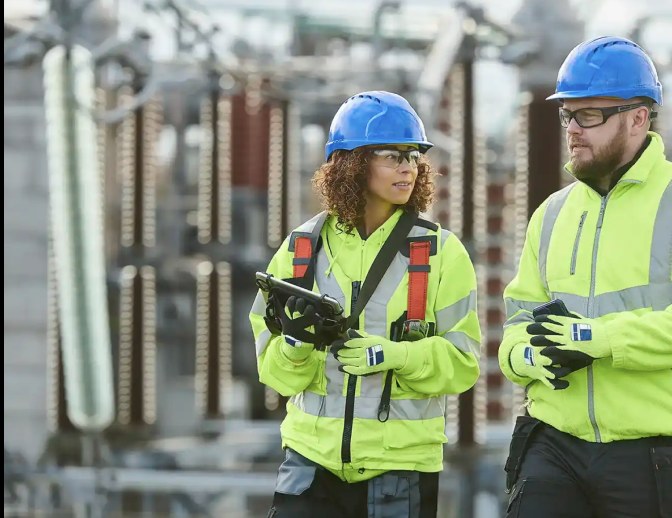 Two field technicians reviewing a tablet at a substation