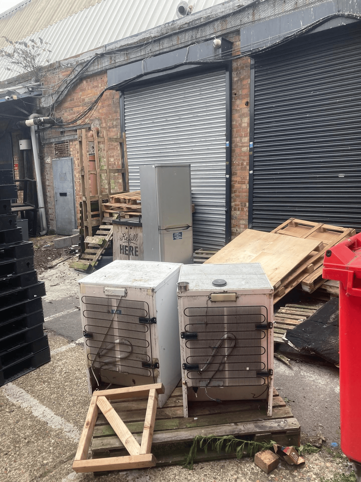 Old fridges and a fridge freezer waiting for collection in a yard