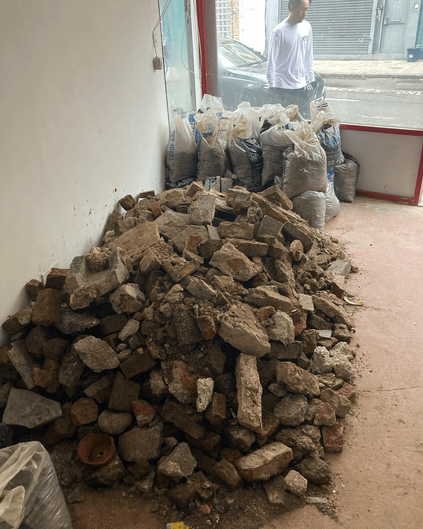 Bagged rubble and a pile of broken bricks inside a shop unit after building work
