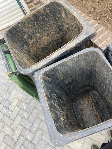 2 emptied wheelie bins standing on a block paved driveway