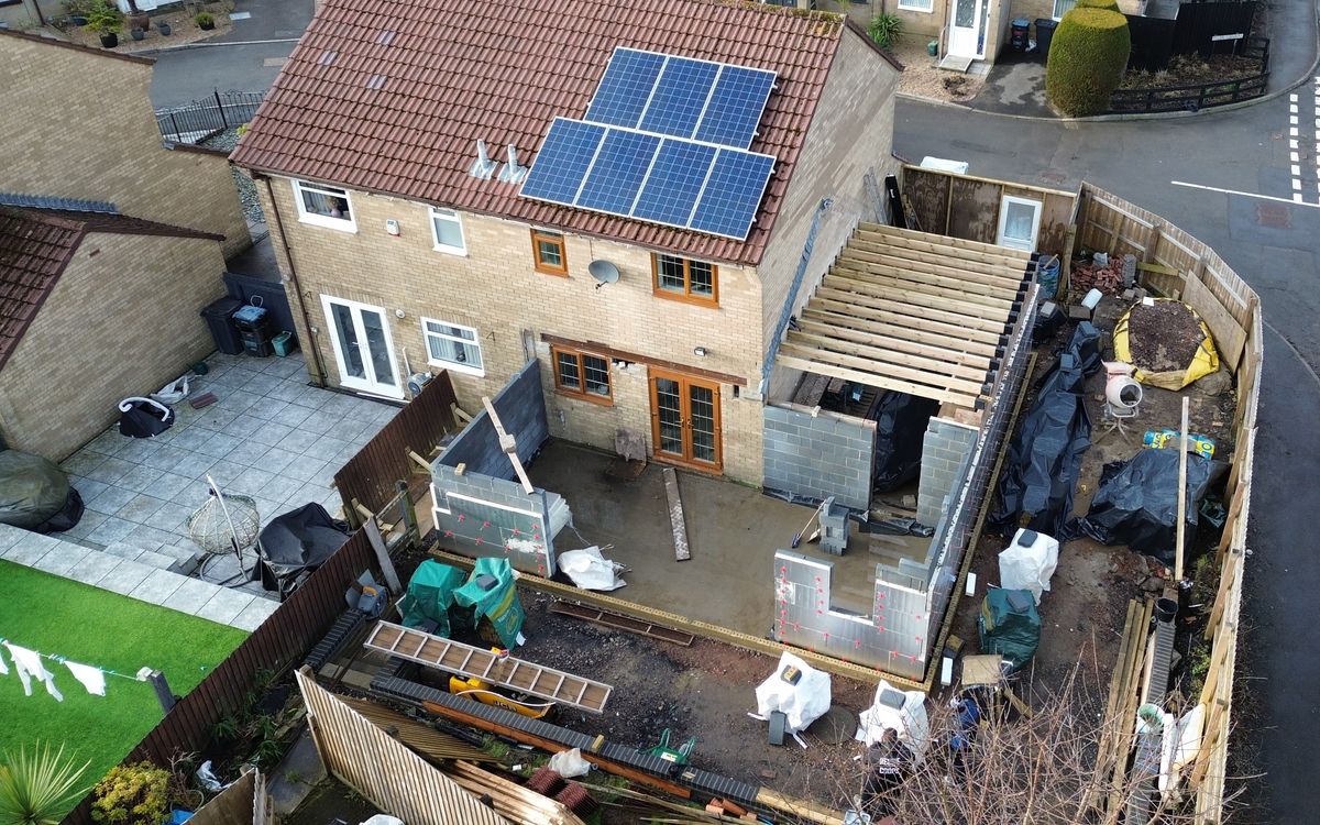 Overhead view of a house extension under construction, showing blockwork walls and roof joists