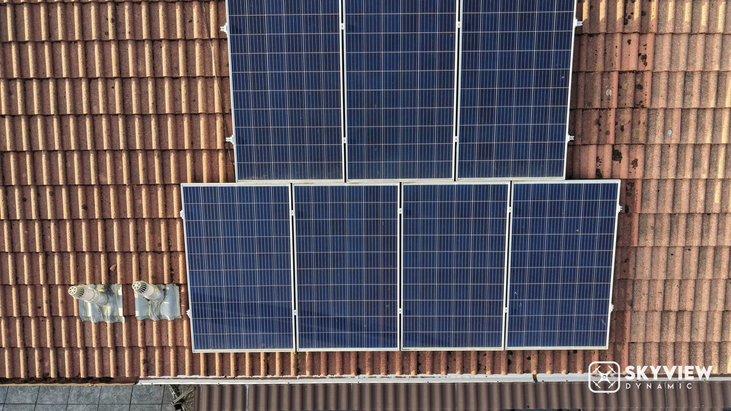 Top-down drone view of solar panels on a tiled roof