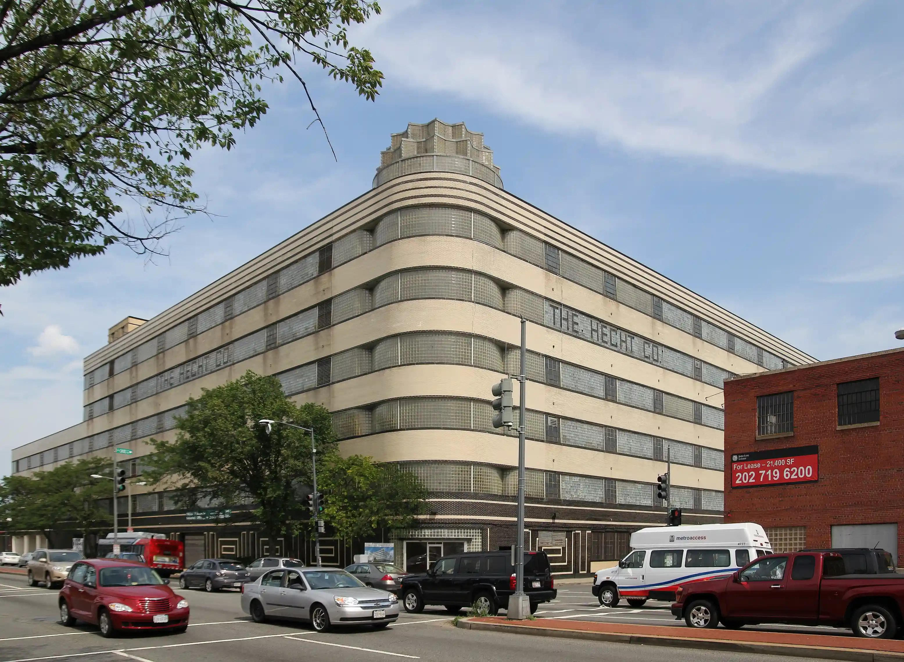 A large building with a rounded corner and glass-block windows beside a Washington, D.C. street.