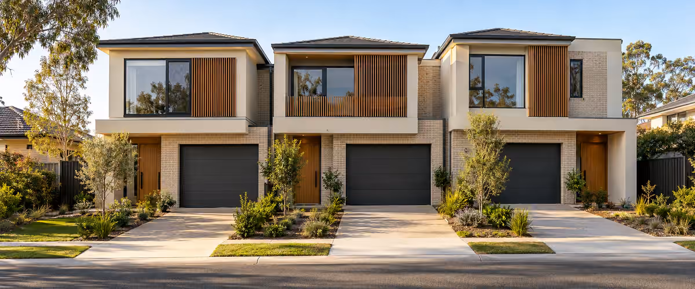 Three attached two-storey homes, each with its own driveway