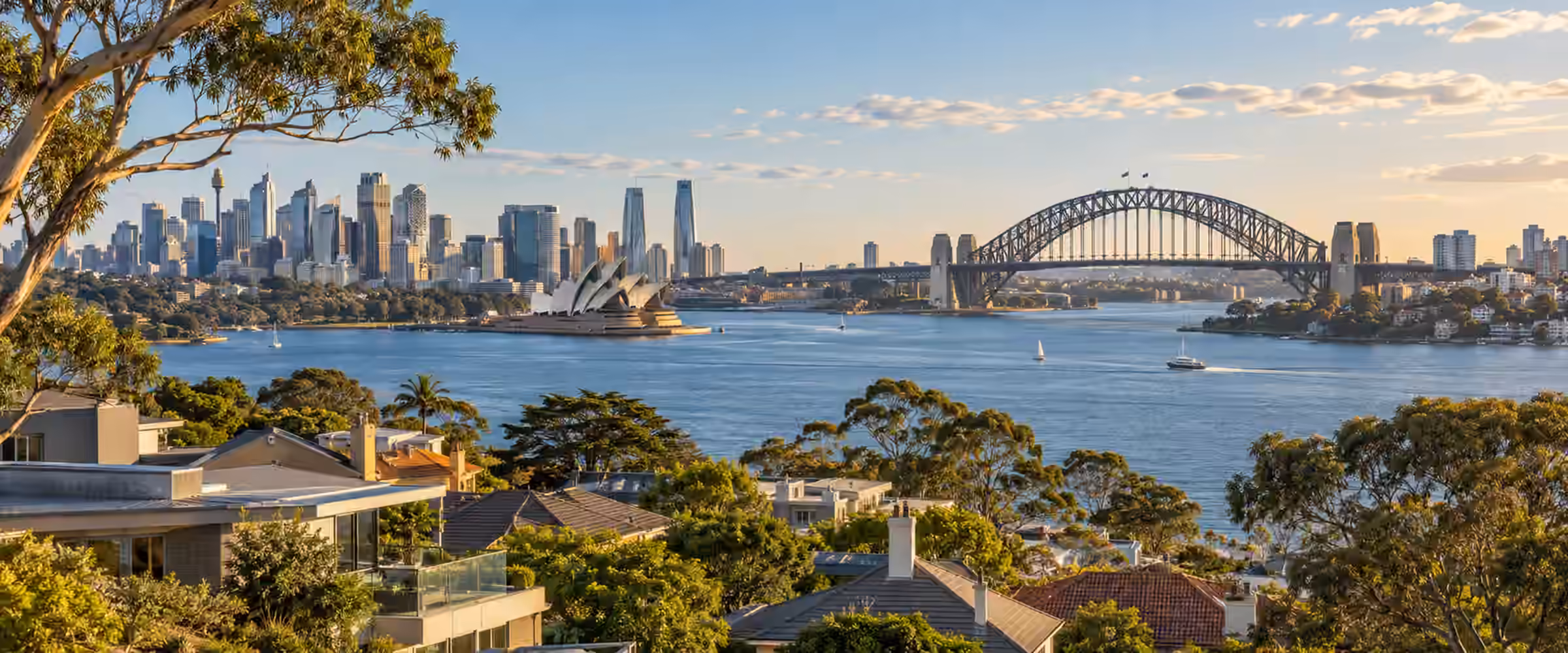 Sydney Harbour, the Harbour Bridge and Opera House seen over North Shore rooftops