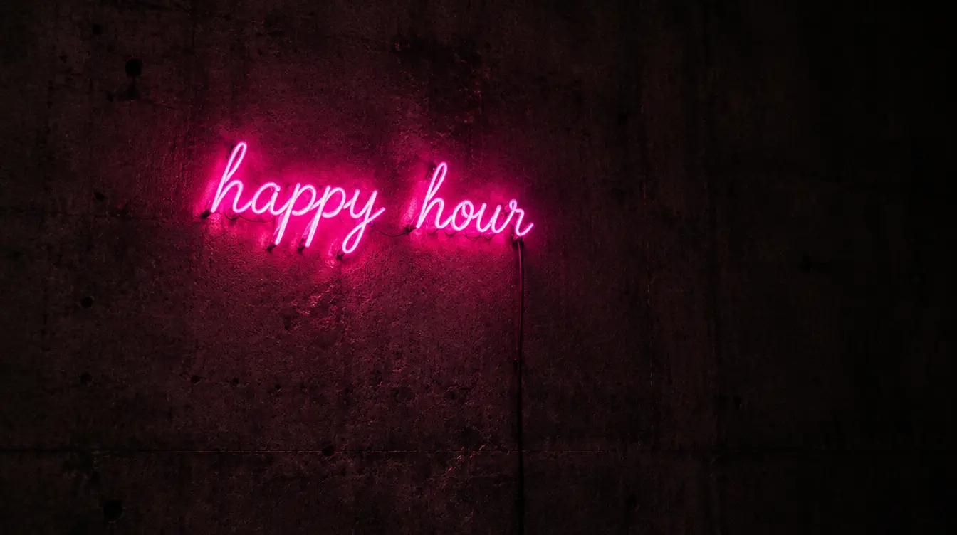 Neonschrift happy hour in Magenta an einer Betonwand