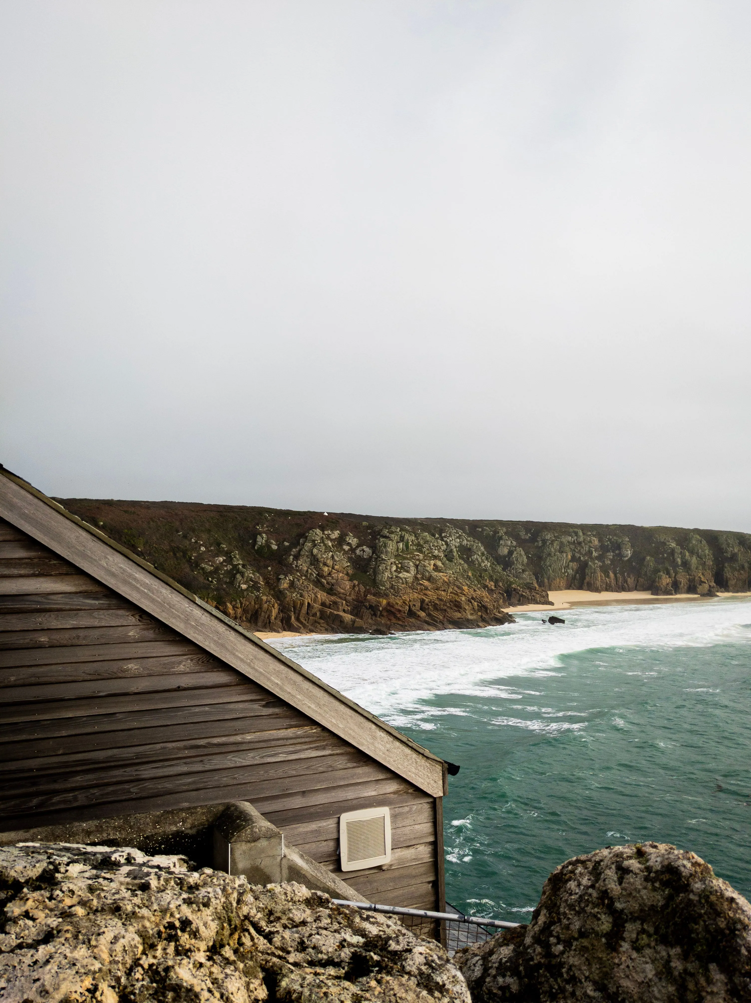 Wooden hut on a Cornish clifftop above a turquoise cove