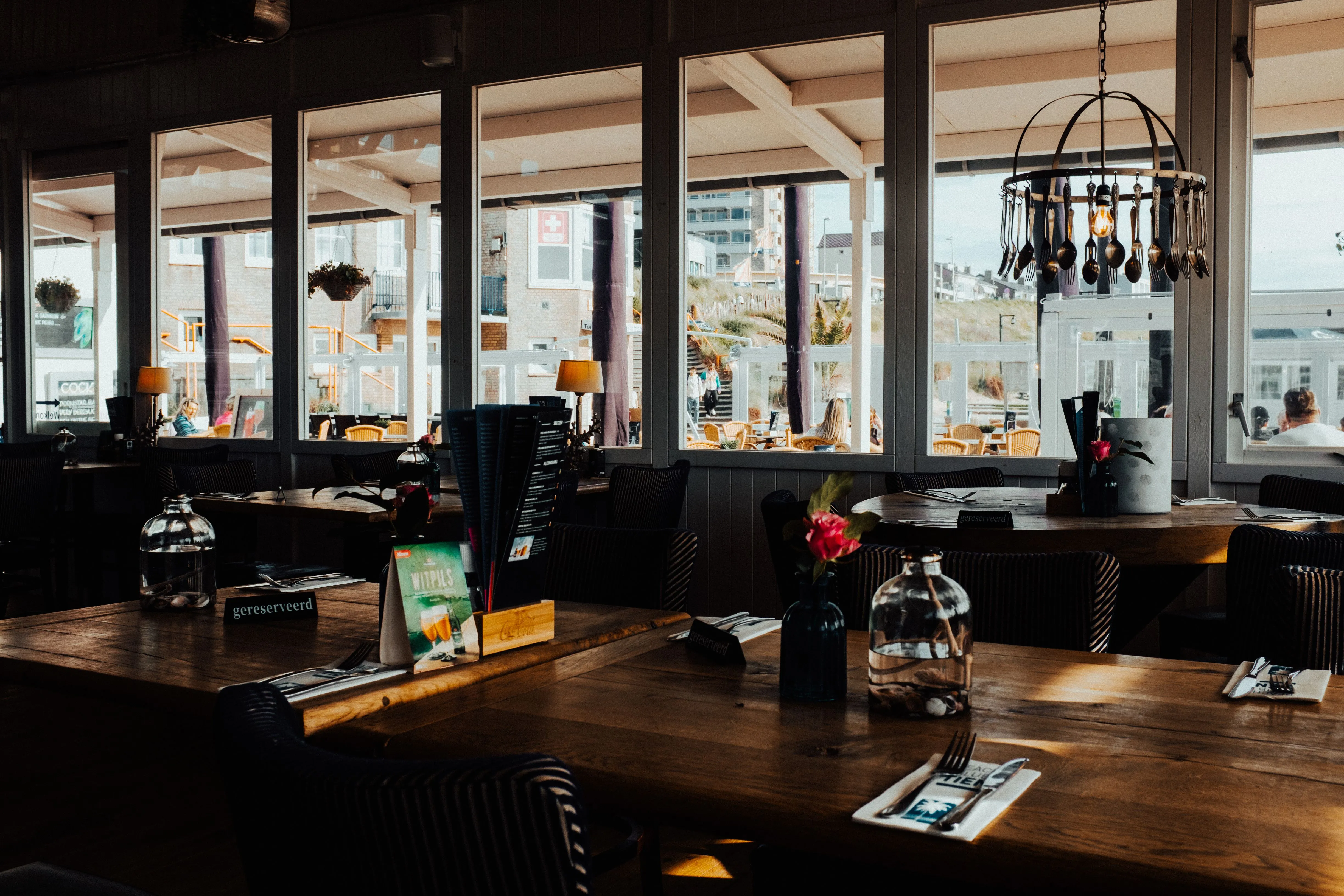 Dark beachfront restaurant interior with wooden tables and a large window