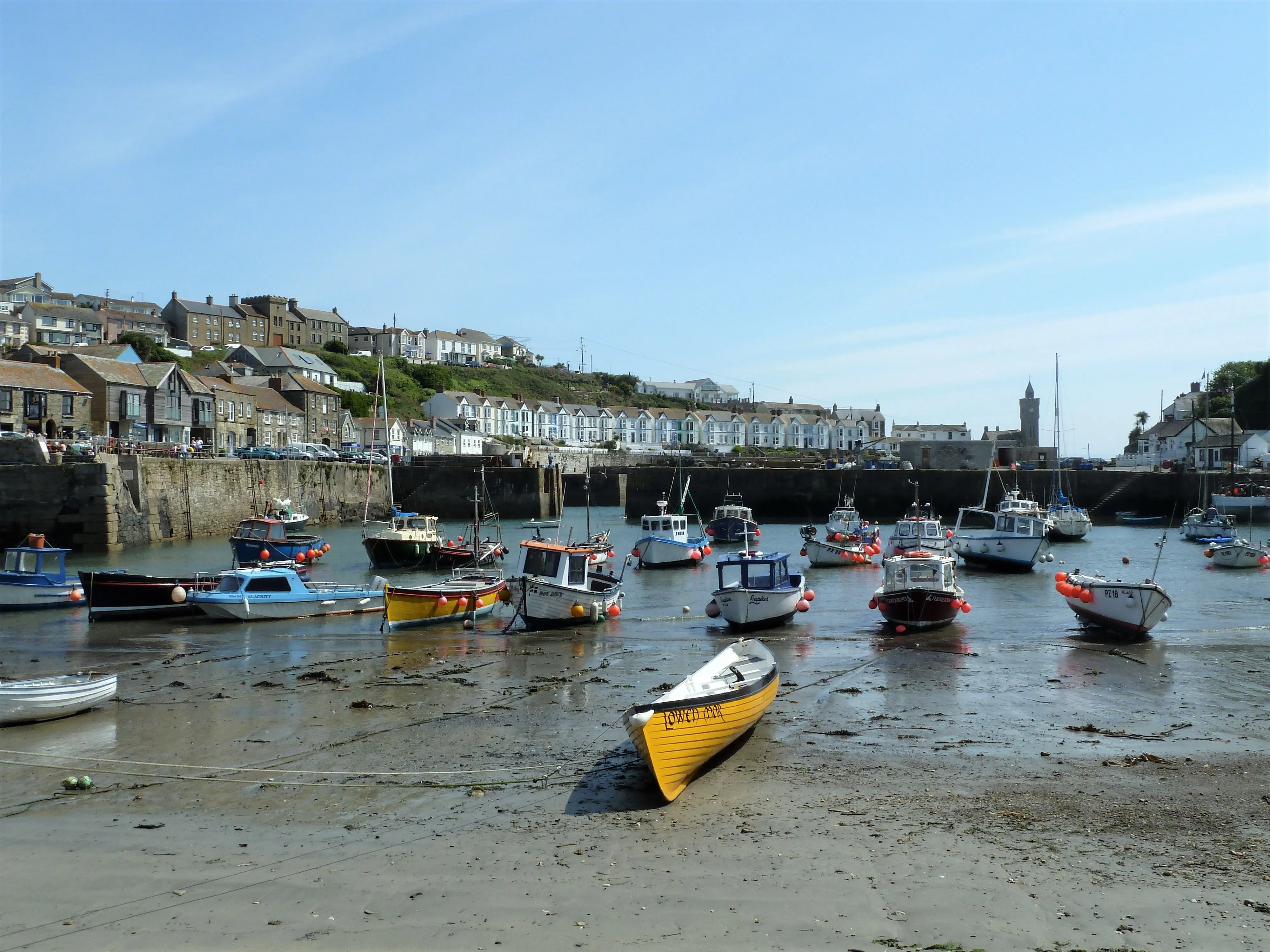 Cornish fishing harbour at low tide with boats and hillside town