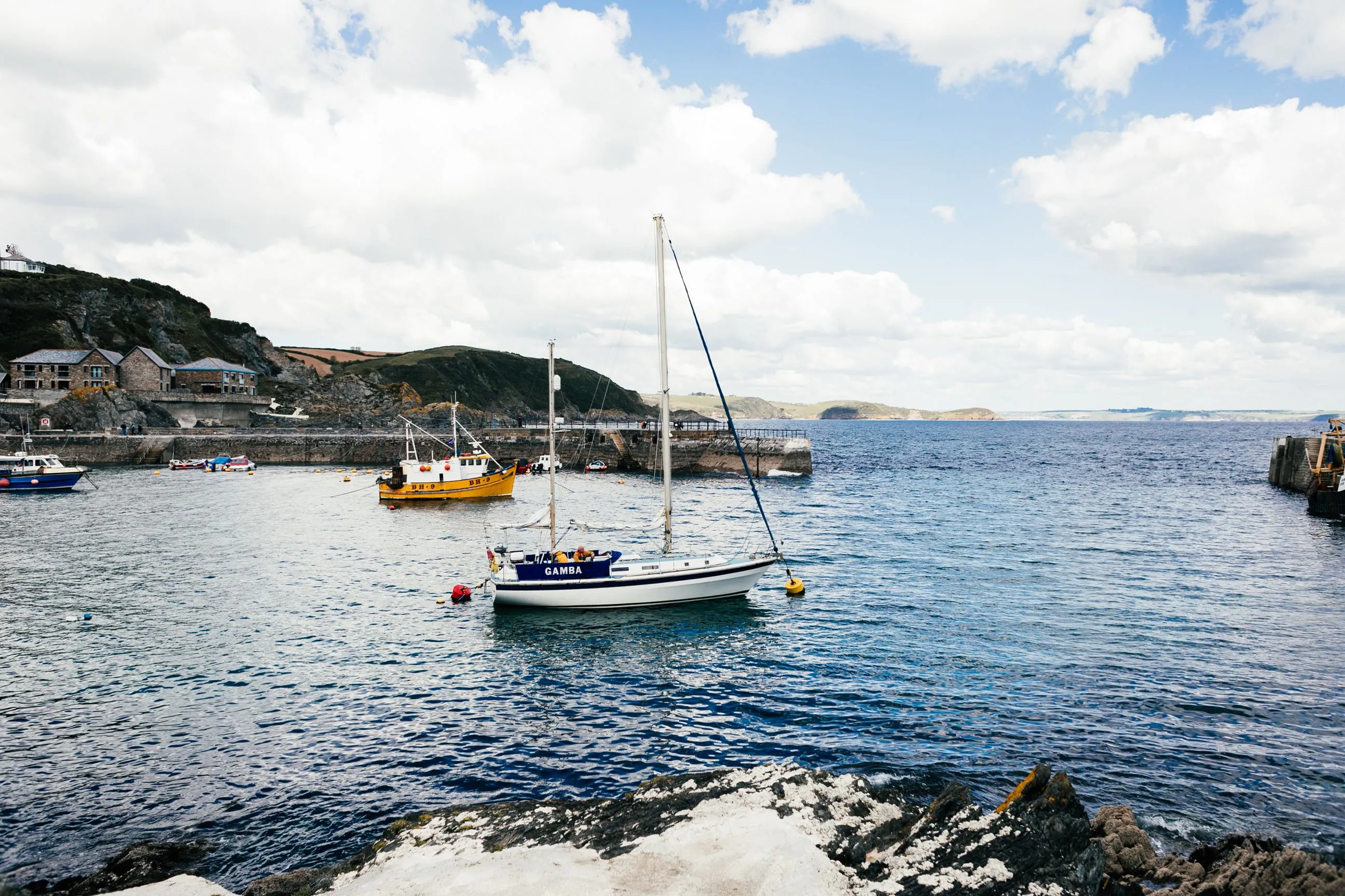 Small Cornish harbour with a yellow fishing boat and stone pier