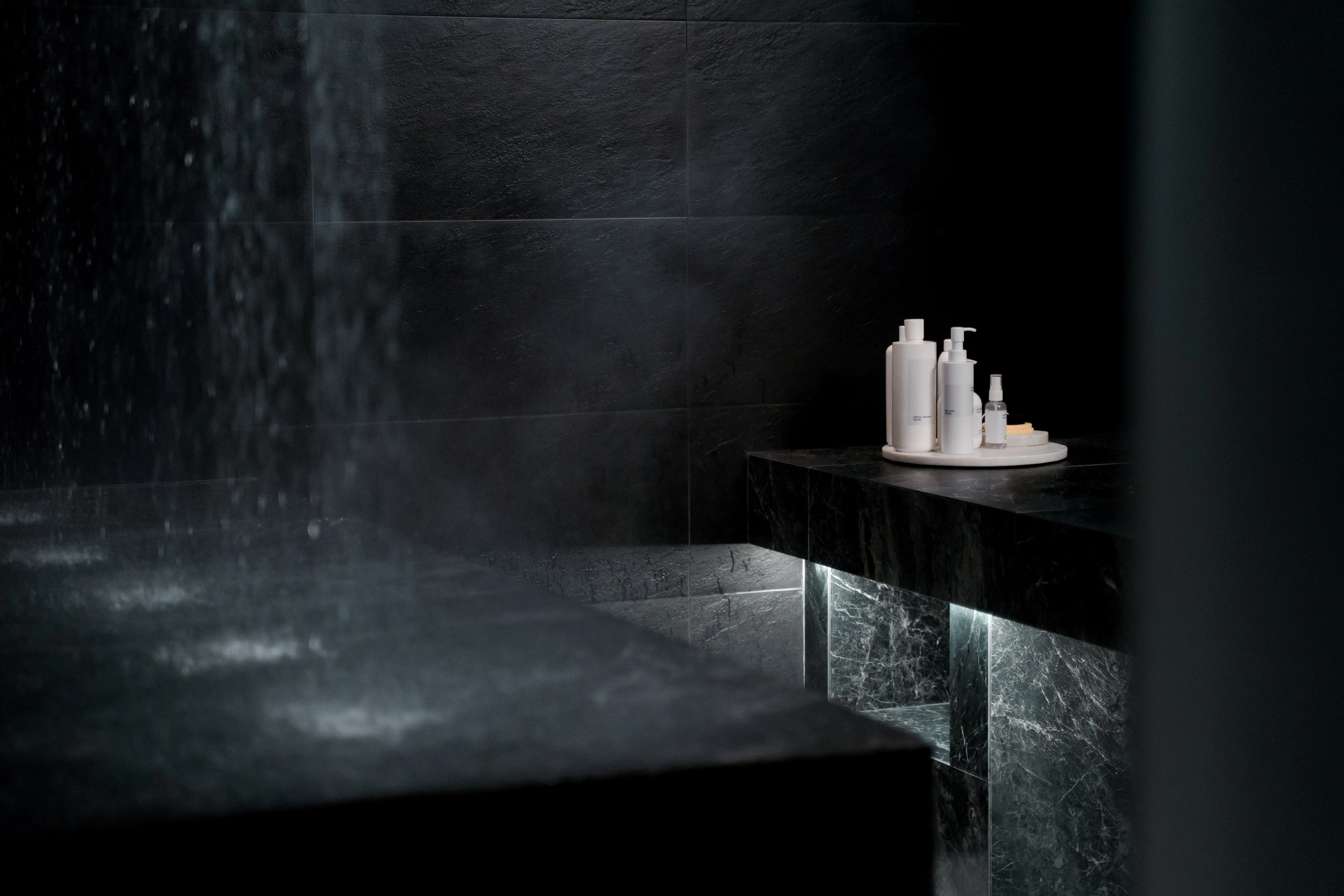 Spa steam room with slate walls and a lit stone bench