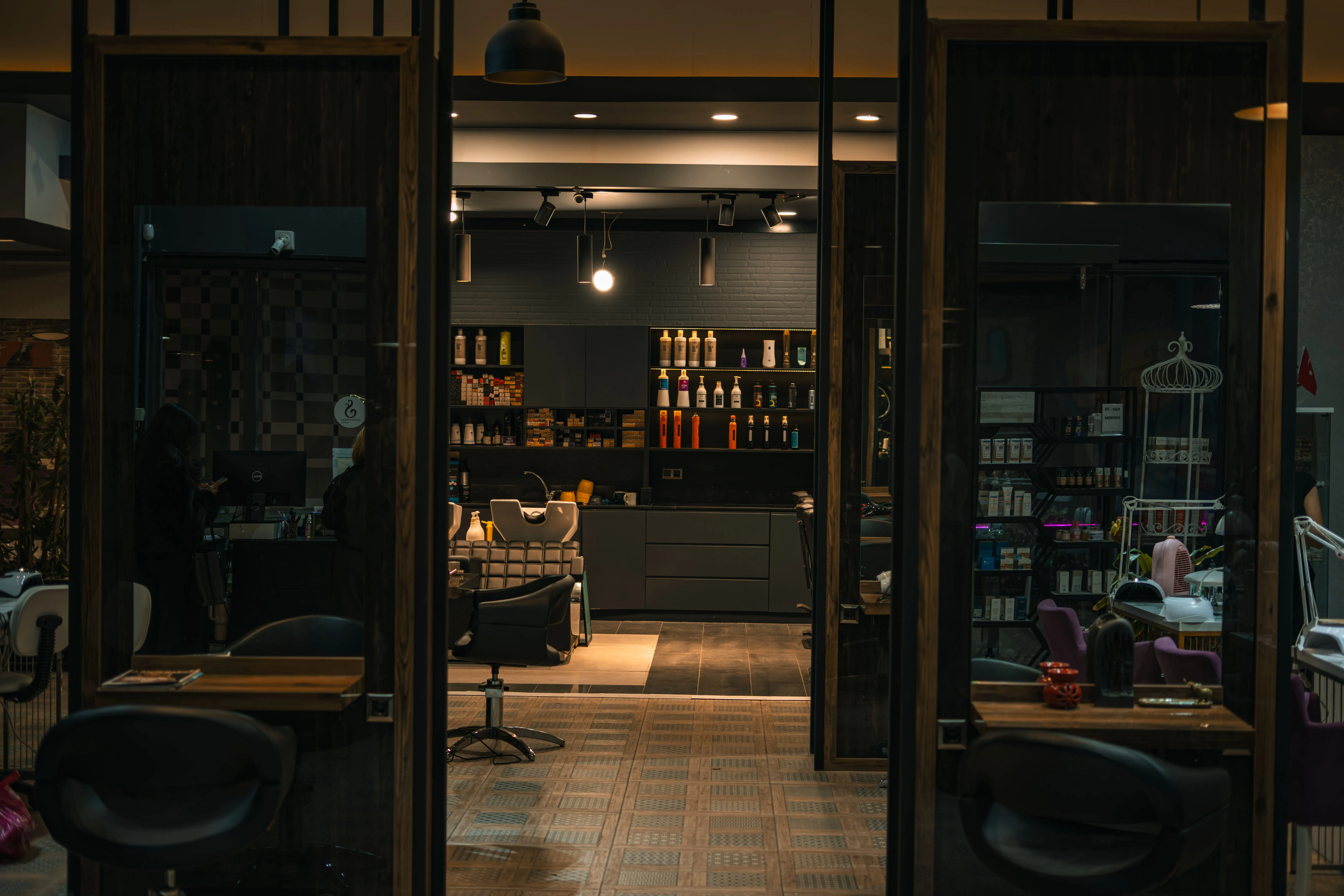 Dimly lit hair salon interior with chairs, shelves and wash basin