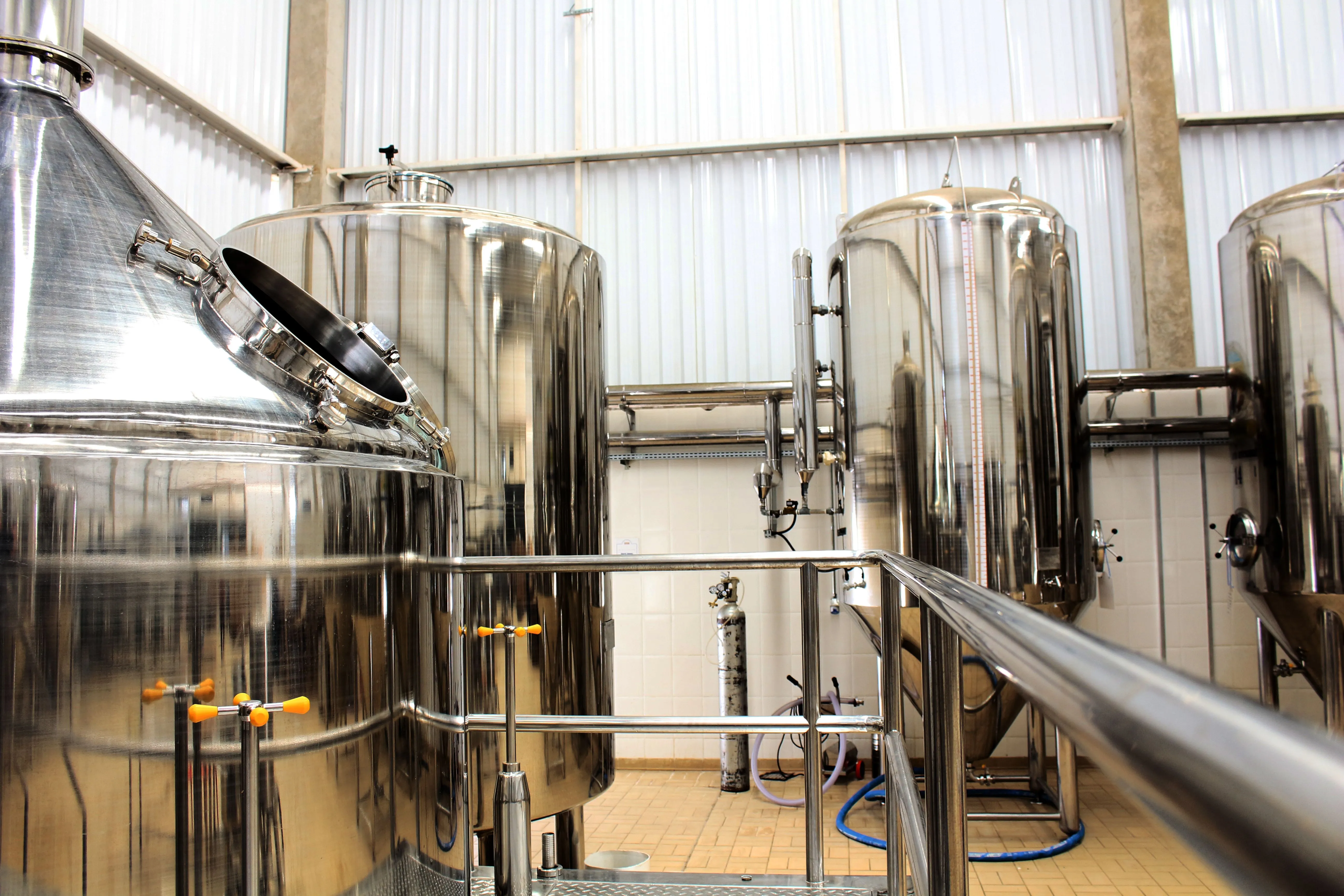 Stainless steel brewery tanks and railings in white industrial hall