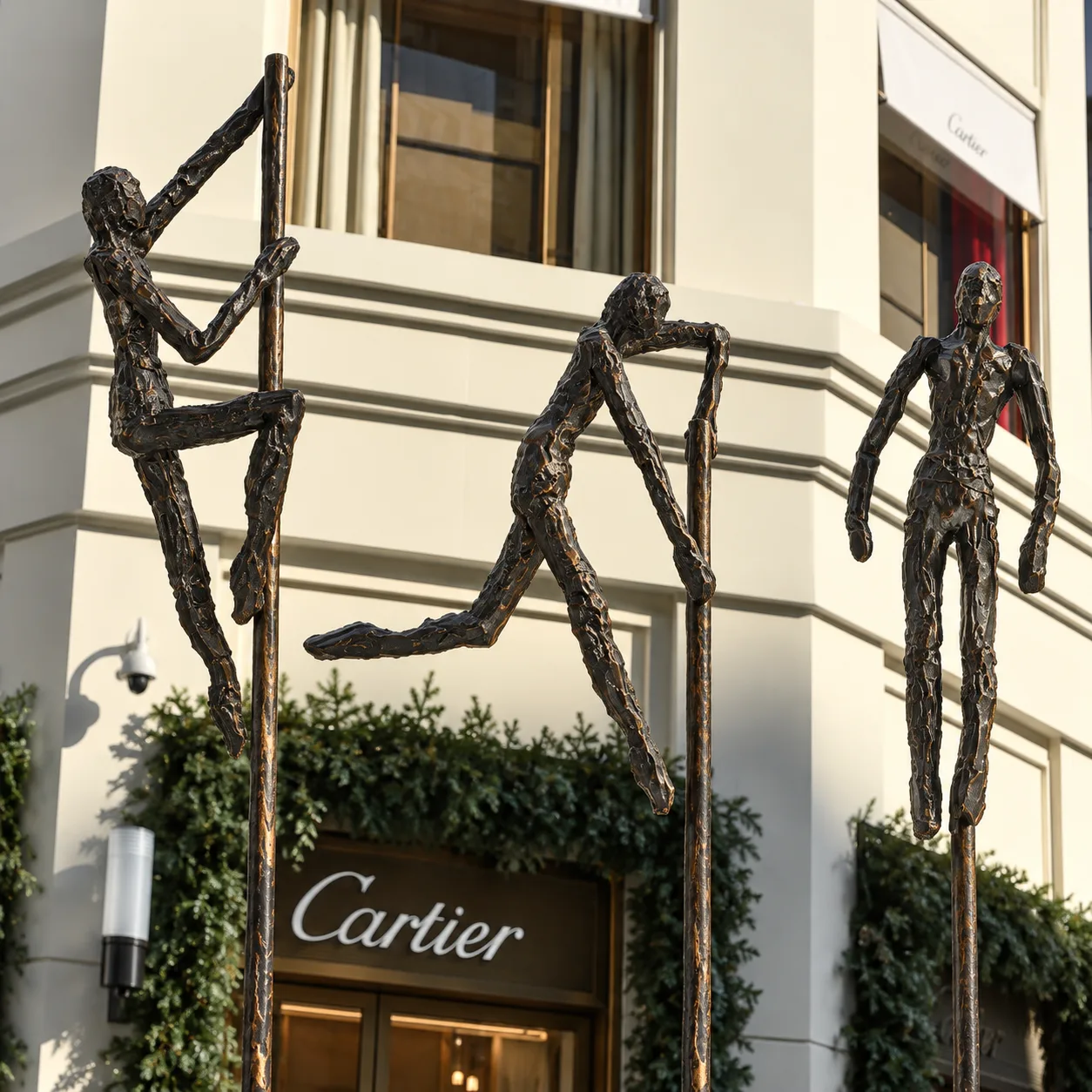 Acting Men'den üç figür, çubukları üzerinde, Cartier cephesinin önünde