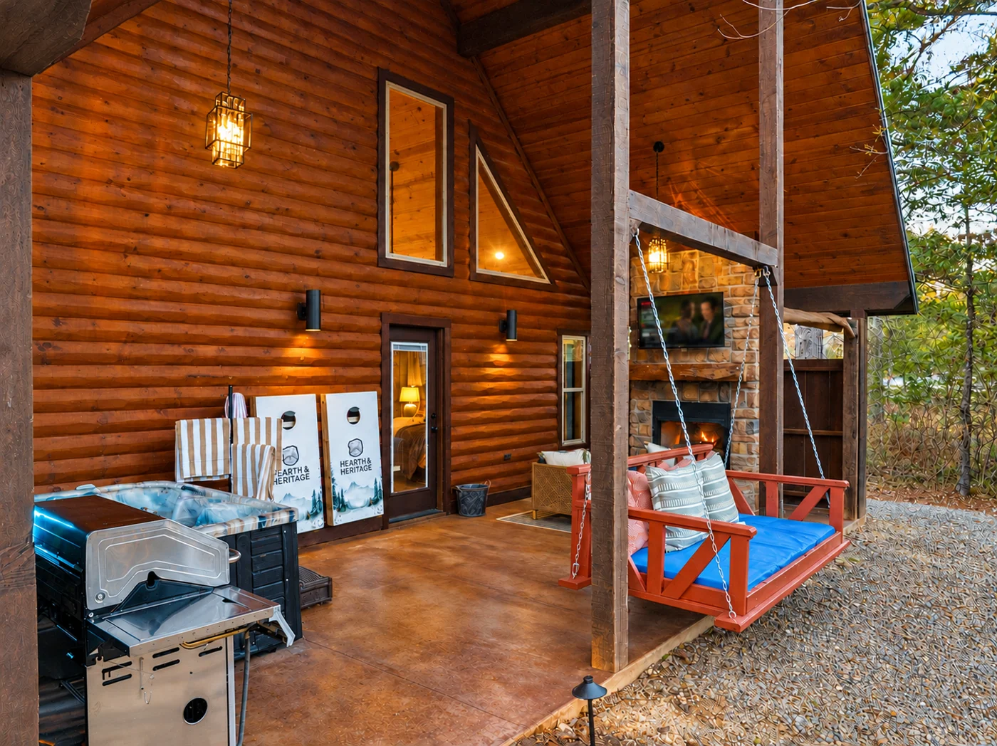 The covered patio at Hearth and Heritage with hot tub, grill, and swing daybed