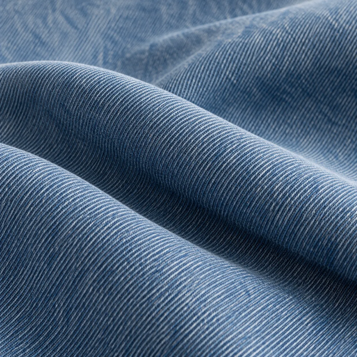 Supple medium-blue denim in fluid diagonal folds.