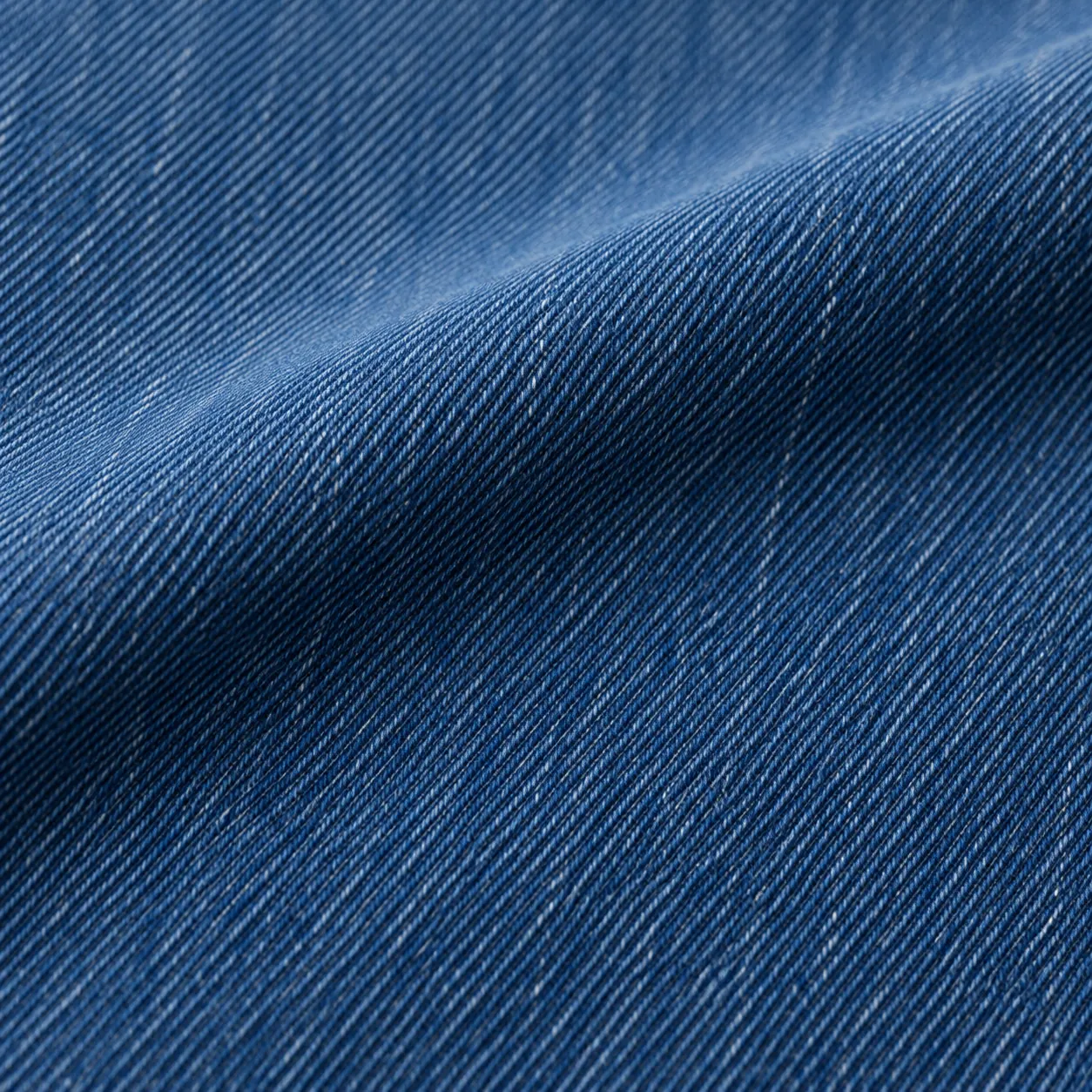 Smooth evenly coloured mid-indigo denim with a shallow fold.