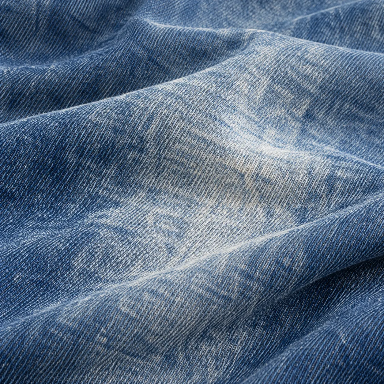 Stone-washed blue denim with softly faded areas and loose shallow folds.