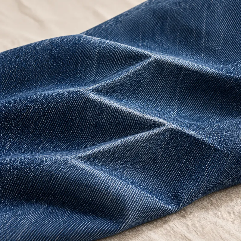 Indigo denim with crisp angular set creases and a subtle coated sheen.