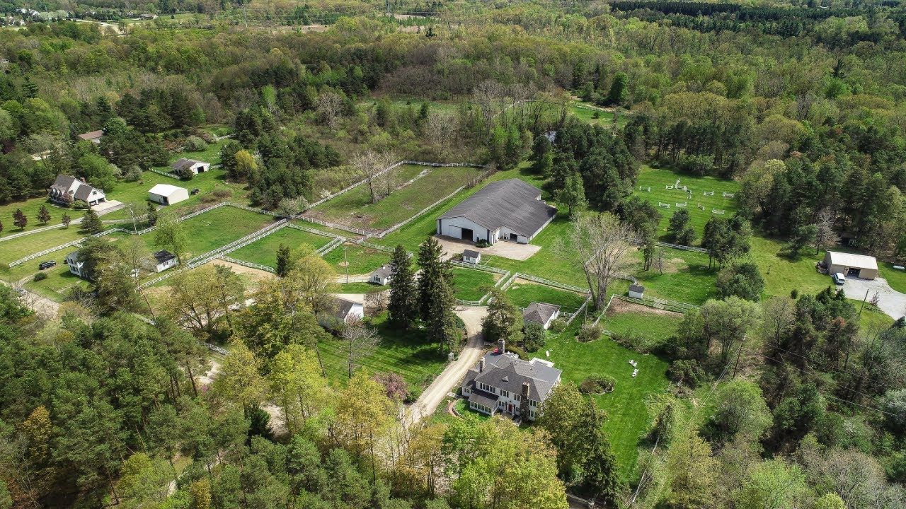 Aerial view of an equestrian property with a barn, paddocks and riding arenas