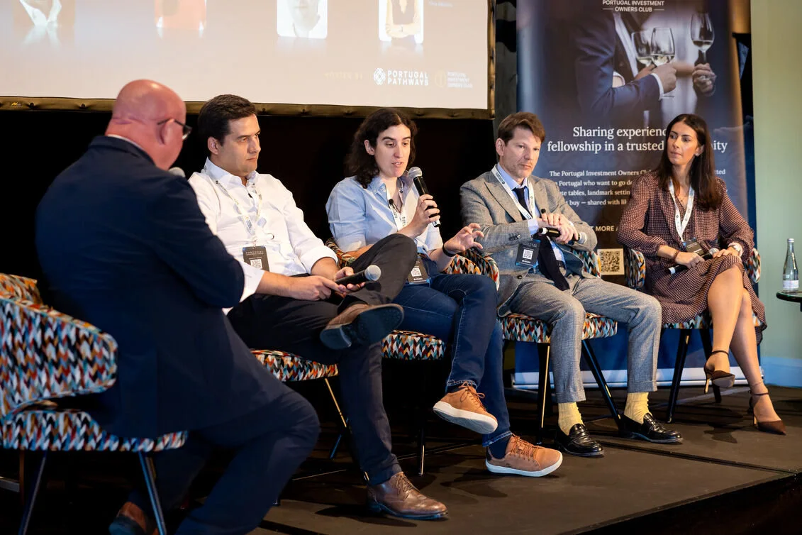 A moderator leads discussion among four panellists on the forum stage